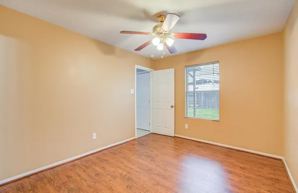 a view of an empty room with wooden floor and a window