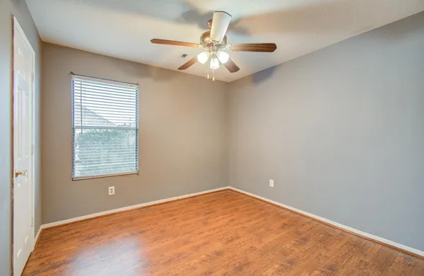 an empty room with a chandelier fan and windows
