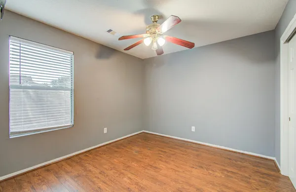an empty room with windows and chandelier fan