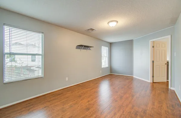 a view of an empty room with wooden floor and a window