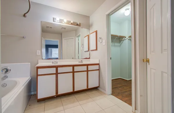 a bathroom with a double vanity sink mirror and bathtub