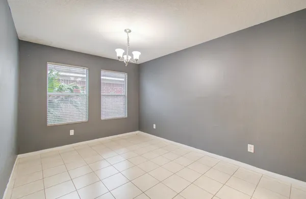an empty room with chandelier fan and window