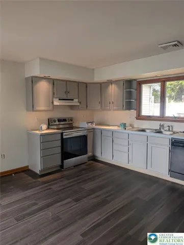 a kitchen with stainless steel appliances granite countertop a white cabinets and a wooden floor