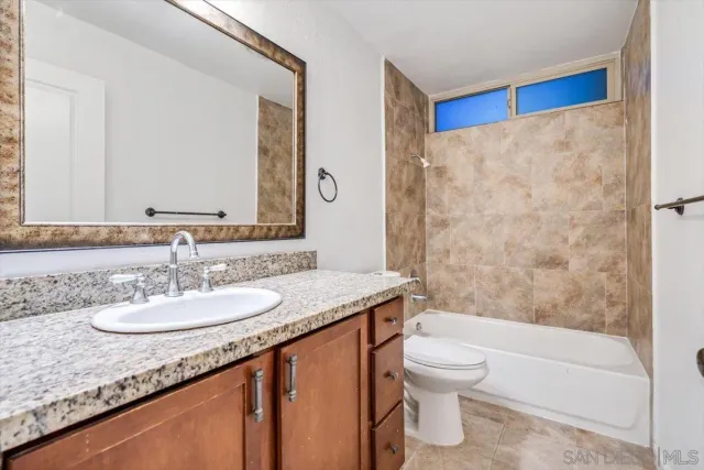 a bathroom with a granite countertop sink a toilet a mirror and bathtub