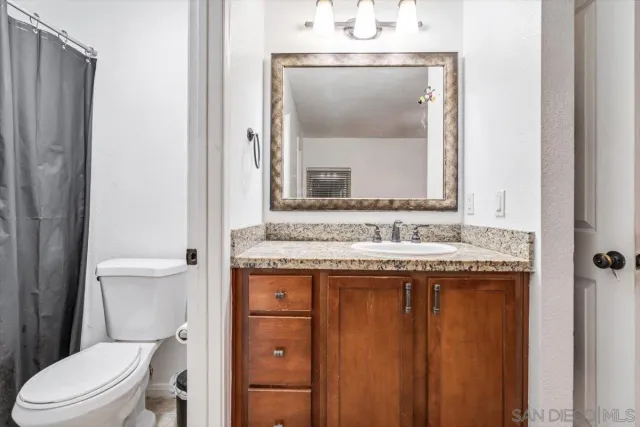 a bathroom with a granite countertop toilet sink and mirror