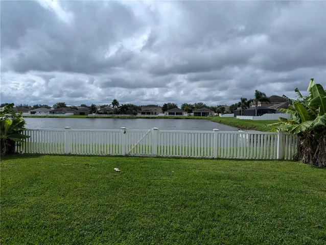 a view of a yard with large trees and wooden fence