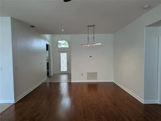 an empty room with wooden floor and a hallway