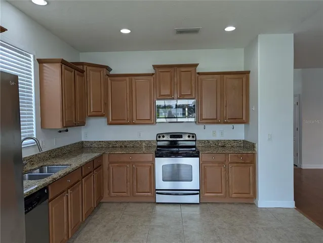 a kitchen with stainless steel appliances granite countertop a stove a sink and a refrigerator