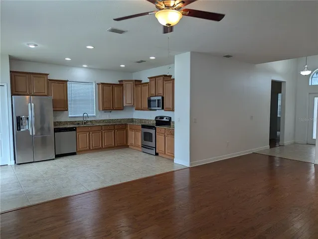 an open kitchen with stainless steel appliances granite countertop a refrigerator oven a sink with wooden floors