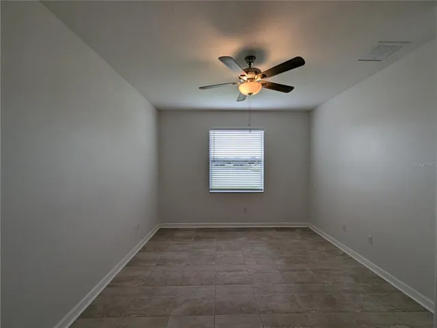 an empty room with a window and a ceiling fan