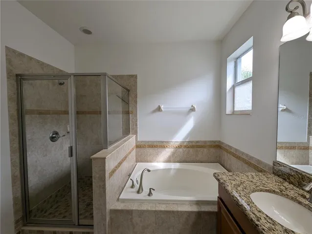 a bathroom with a granite countertop tub sink and mirror