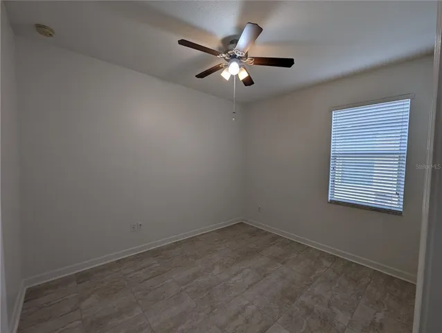 an empty room with a window and a fan