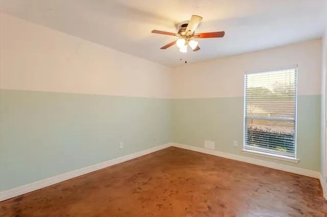an empty room with a window and a fan