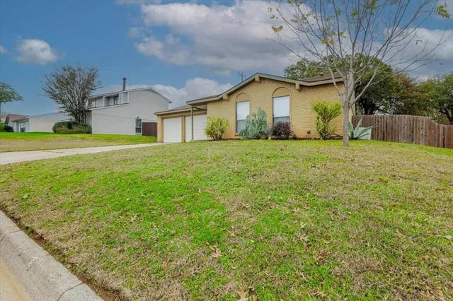 a front view of house with yard and trees in the background