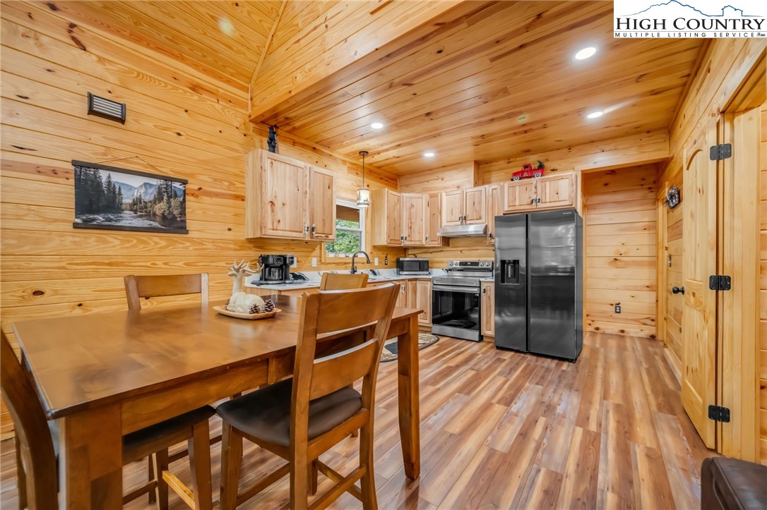 2533 Buck Mountain Road Purlear, NC 28665 - Photo 15 of 40 a kitchen with stainless steel appliances a refrigerator a stove a sink dishwasher a dining table and chairs with wooden floor