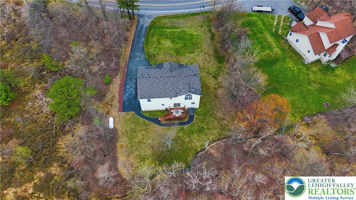 2742 Long Pond Road Long Pond, PA 18334 - Photo 2 of 57 An aerial perspective reveals a private home nestled amidst a verdant landscape, featuring a paved driveway and a welcoming deck.