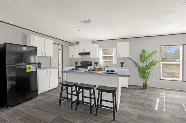 a kitchen with stainless steel appliances a dining table chairs refrigerator and microwave