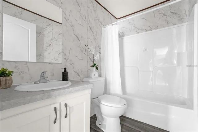 a bathroom with a granite countertop sink a toilet and shower