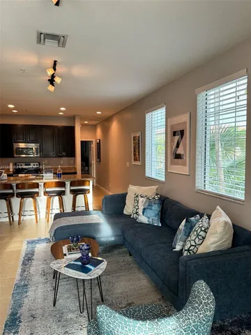 a living room with furniture couches and kitchen view