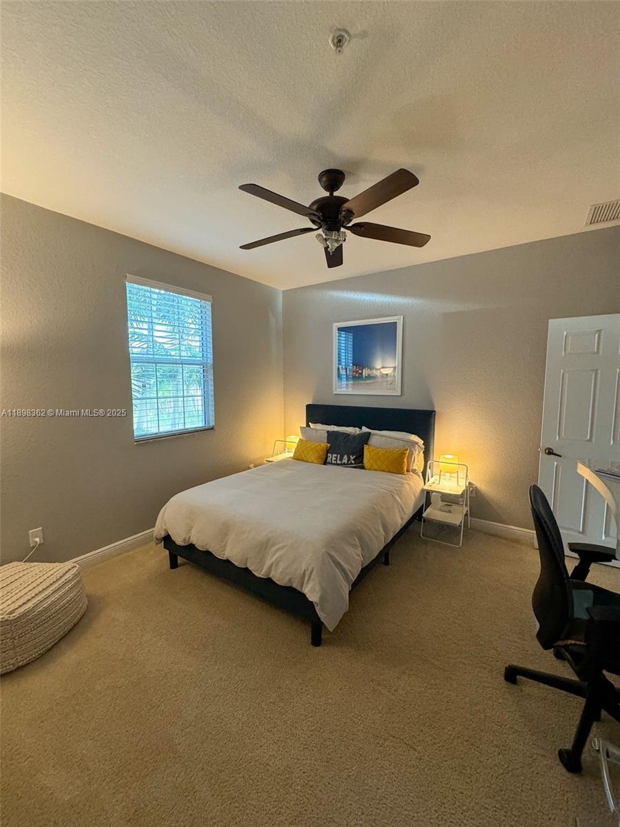 1006 Southwest 147th Avenue, Unit 10601 Pembroke Pines, FL 33027 - Photo 31 of 38 a bedroom with a bed a chair and potted plant on the dresser