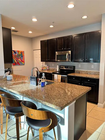 a kitchen with stainless steel appliances granite countertop a stove top oven a sink a dining table and chairs