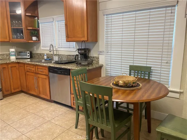 a kitchen with stainless steel appliances granite countertop a dining table chairs and a refrigerator