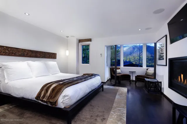 a bedroom with a bed a couch and a flat tv screen on a dresser