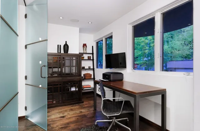 a table room with chairs a flat screen tv and floor to ceiling window