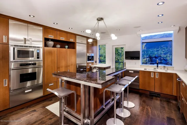a kitchen with stainless steel appliances kitchen island granite countertop a table chairs in it and wooden floors