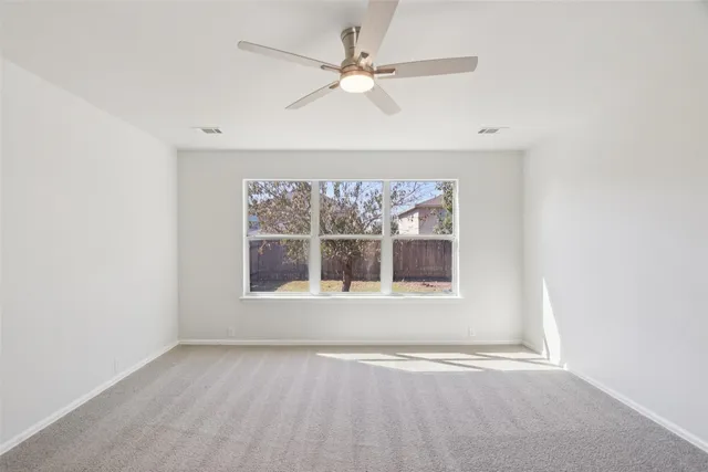 an empty room with a window and a ceiling fan