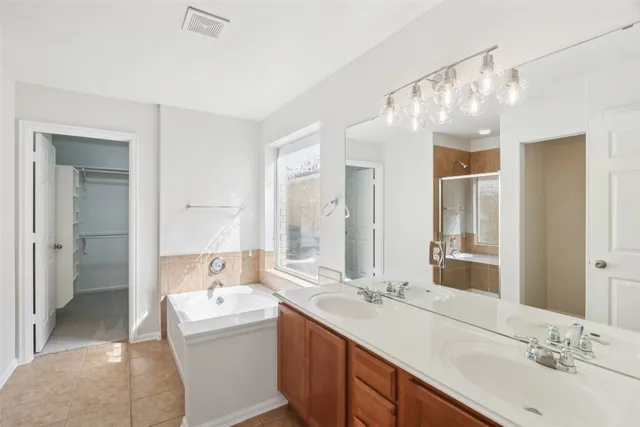 a bathroom with a sink double vanity granite tub shower and a mirror