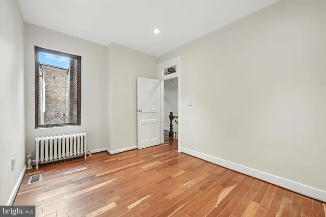 an empty room with wooden floor and a window