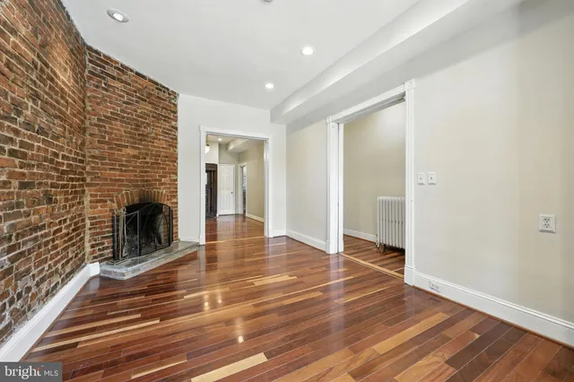 a view of a livingroom with wooden floor and a fireplace