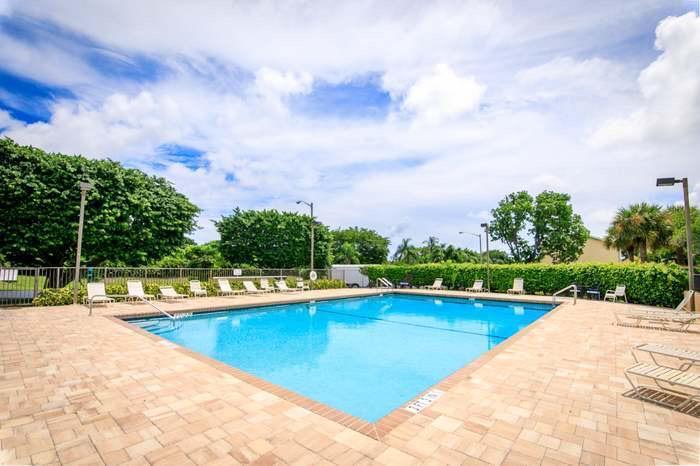 117 Waterside Drive, Unit 117 Hypoluxo, FL 33462 - Photo 16 of 19 a view of swimming pool that has lawn chairs with plants and lake view