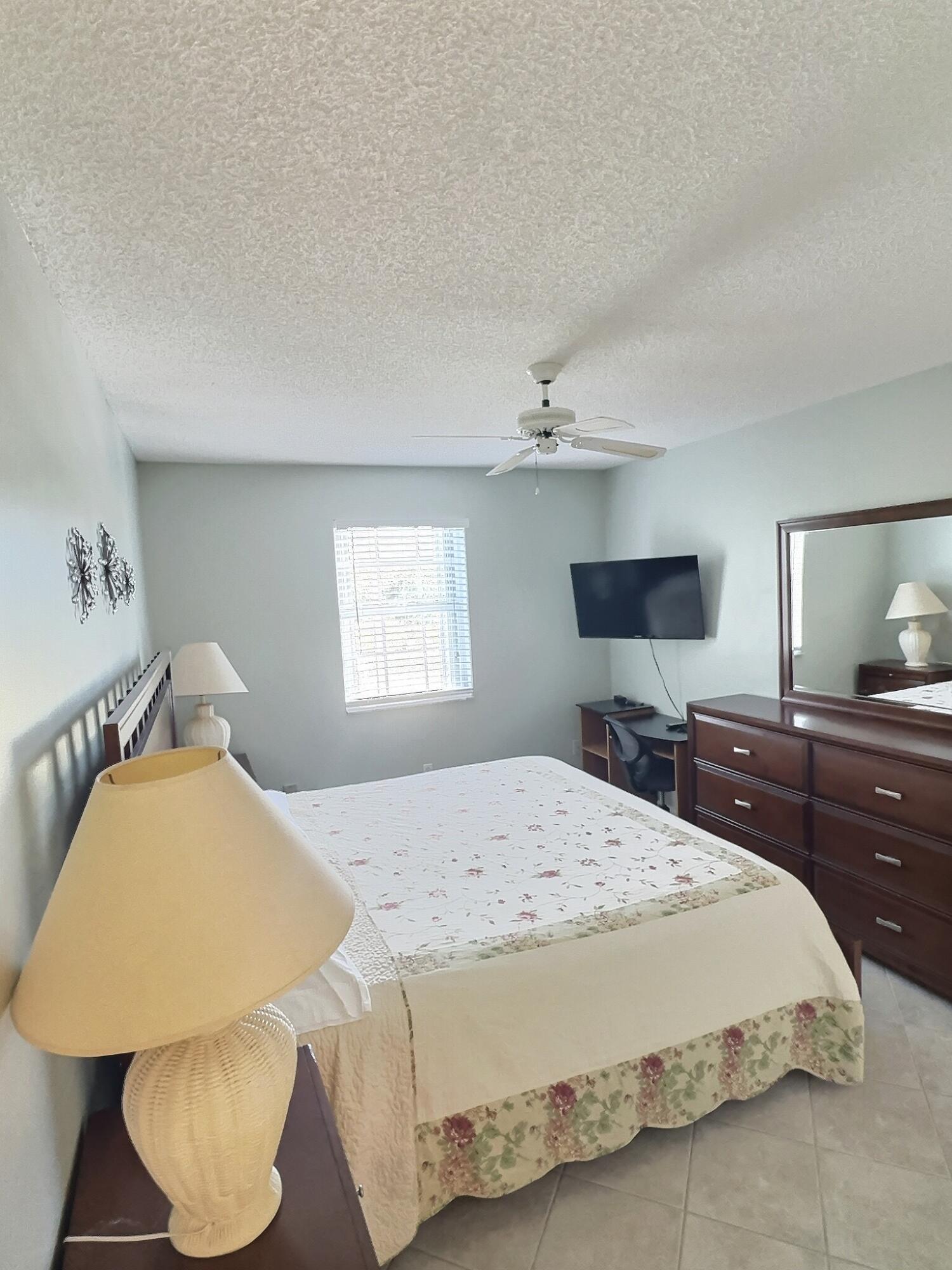 117 Waterside Drive, Unit 117 Hypoluxo, FL 33462 - Photo 8 of 19 a bedroom with a bed and a flat screen tv