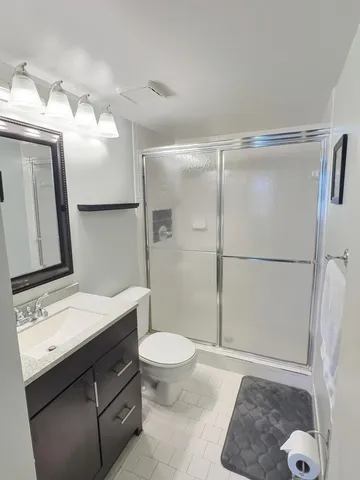 a bathroom with a sink a toilet a mirror and shower