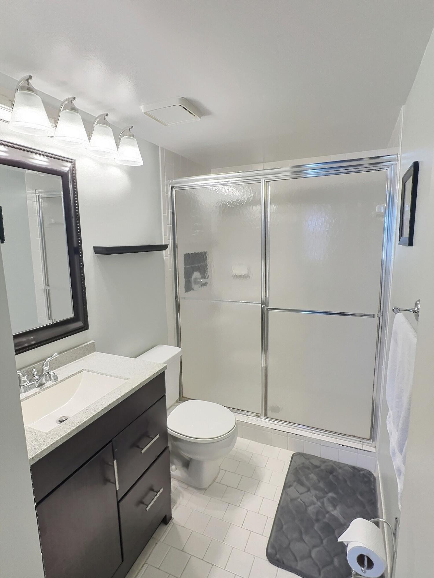 117 Waterside Drive, Unit 117 Hypoluxo, FL 33462 - Photo 9 of 19 a bathroom with a sink a toilet a mirror and shower