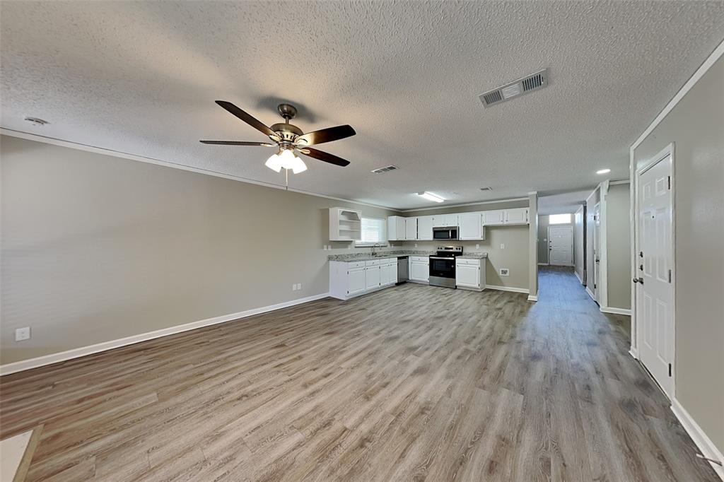 7309 Indiana Avenue Fort Worth, TX 76137 - Photo 4 of 18 Unfurnished living room with light wood-style floors, a textured ceiling, and ceiling fan