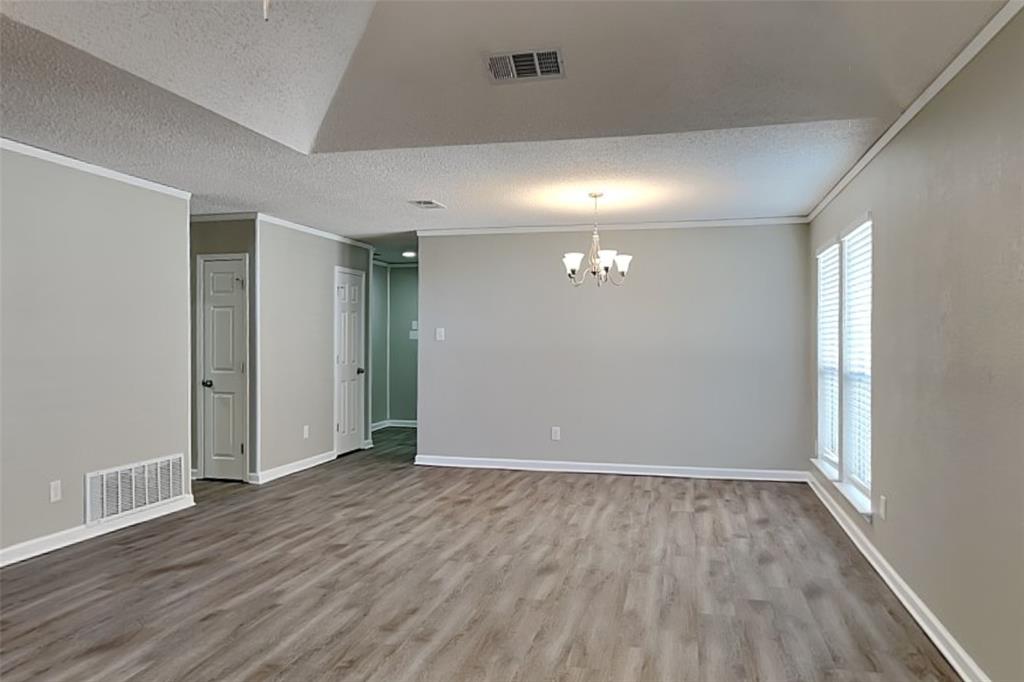 7309 Indiana Avenue Fort Worth, TX 76137 - Photo 6 of 18 Empty room featuring a textured ceiling, wood finished floors, a chandelier, and crown molding