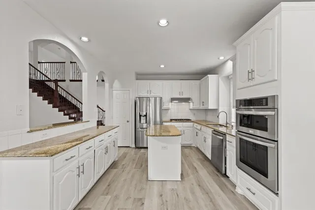 a kitchen with white cabinets and stainless steel appliances