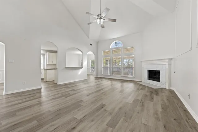 an empty room with wooden floor fireplace and windows