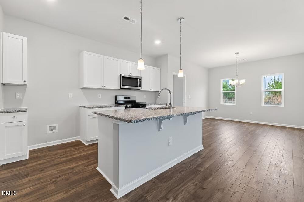 460 Hallingsfield Way Zebulon, NC 27597 - Photo 7 of 31 a kitchen with stainless steel appliances granite countertop a stove a sink and a wooden floors