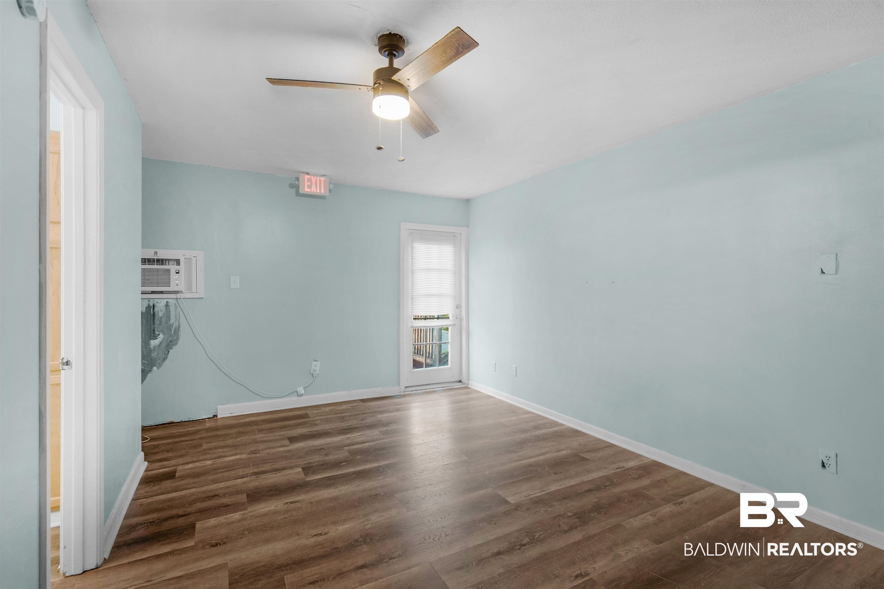 28290 Canal Road Orange Beach, AL 36561 - Photo 14 of 32 Spare room featuring baseboards, a ceiling fan, a wall mounted AC, and wood finished floors