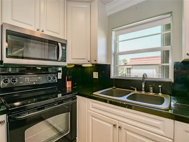 a kitchen with granite countertop a sink stainless steel appliances and cabinets