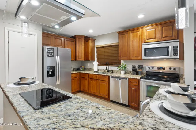 a kitchen with stainless steel appliances granite countertop a sink stove microwave and refrigerator