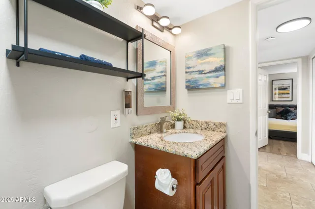a bathroom with a granite countertop sink toilet and mirror