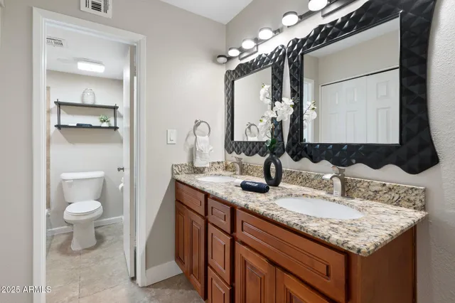 a bathroom with a granite countertop sink a toilet and a mirror