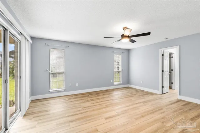 a view of an empty room with a window and a ceiling fan