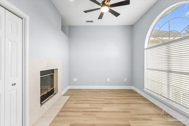 an empty room with wooden floor fan and windows