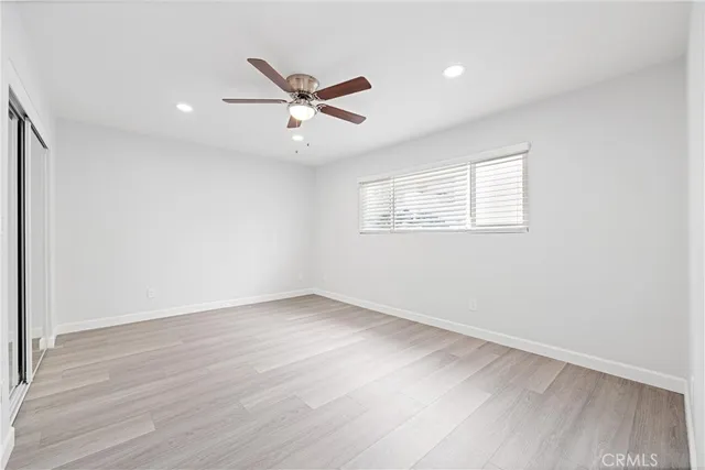 an empty room with wooden floor cabinet and ceiling fan